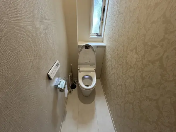 アクセントクロスが可愛らしい印象のトイレ空間。快適に使える、温水洗浄便座付きです。