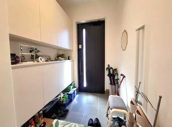 ドアのスリットから自然光が差し込む、明るい玄関。お掃除のしやすいフロートタイプの収納です。